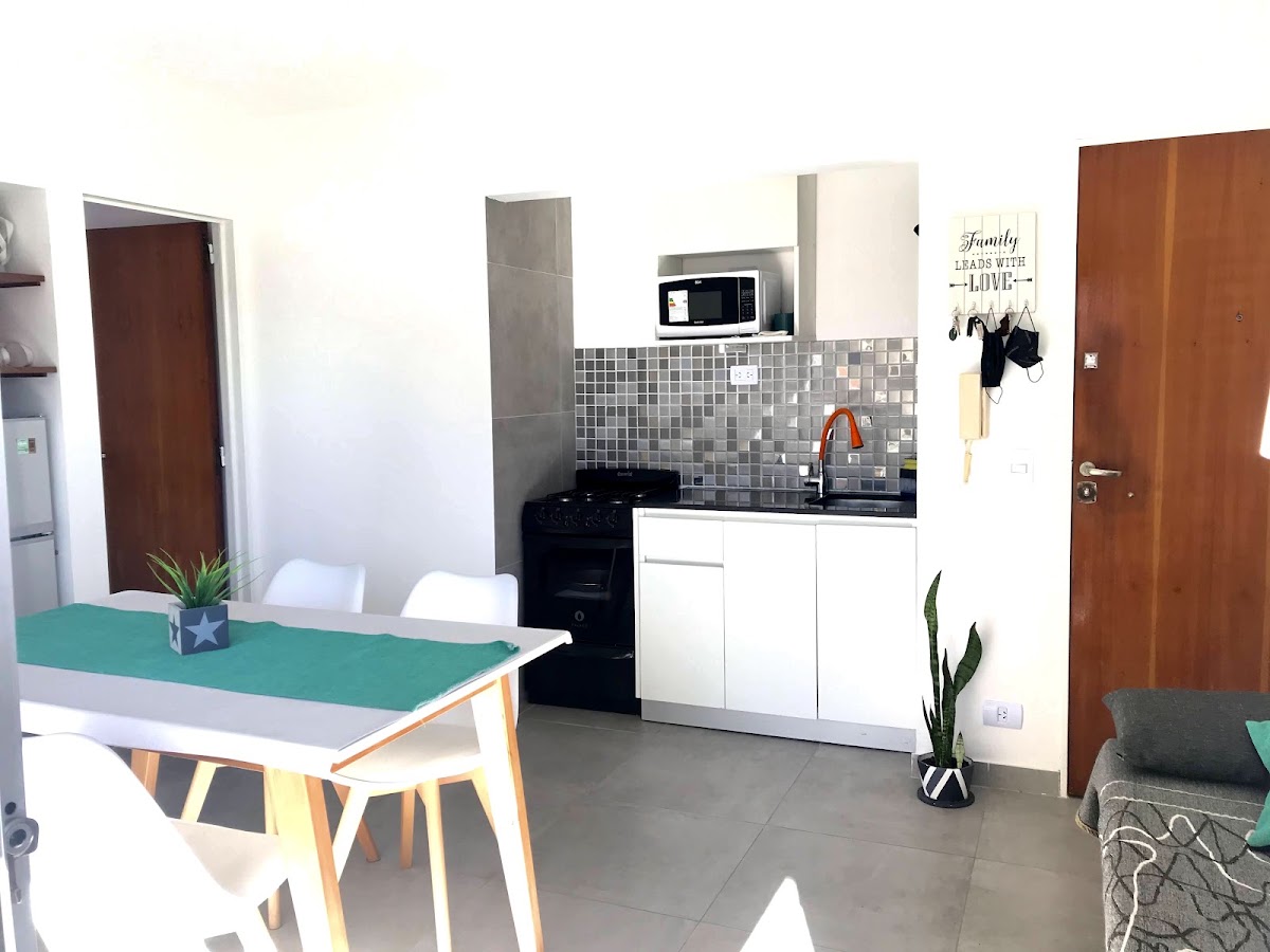 Living con sofá cama, mesa de comedor y puerta de entrada de madera