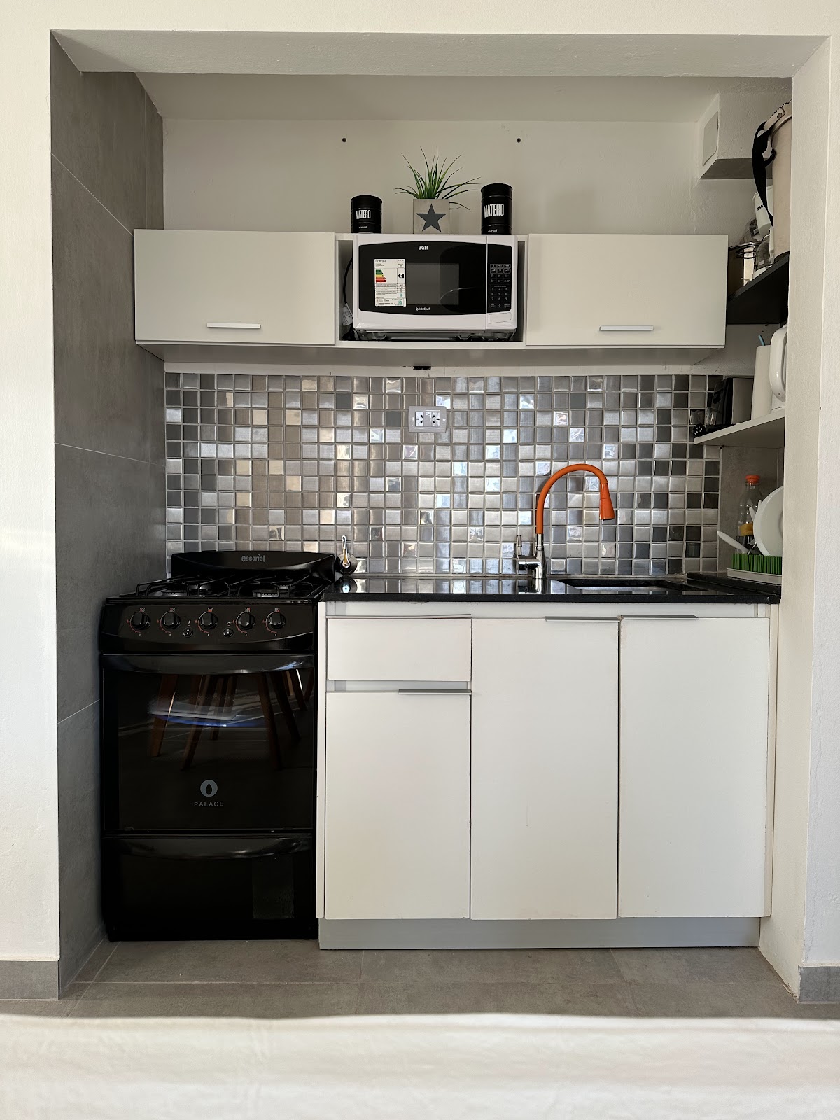 Cocina completa con horno a gas, microondas y grifería naranja
